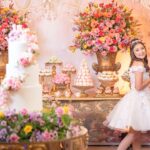 Luxurious quinceañera celebration with opulent flower arrangements and a smiling teenage girl in a white dress.