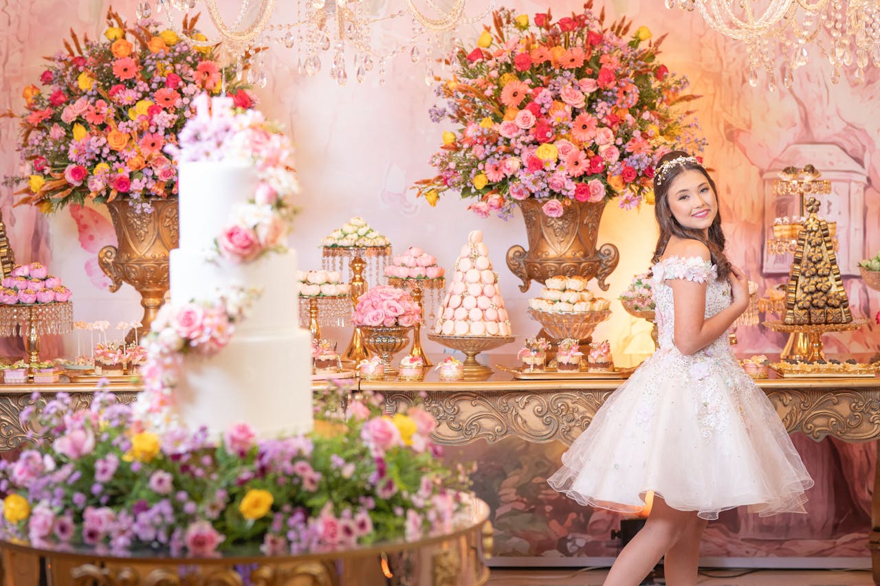 Luxurious quinceañera celebration with opulent flower arrangements and a smiling teenage girl in a white dress.